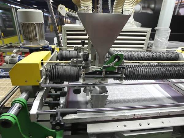 A machine is screen printing ceramic tiles.