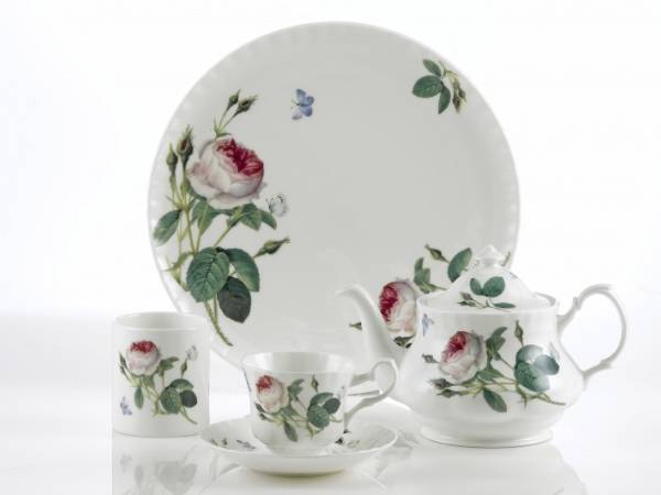 A dish, two cup and teapot with screen printed flower pattern on the table.